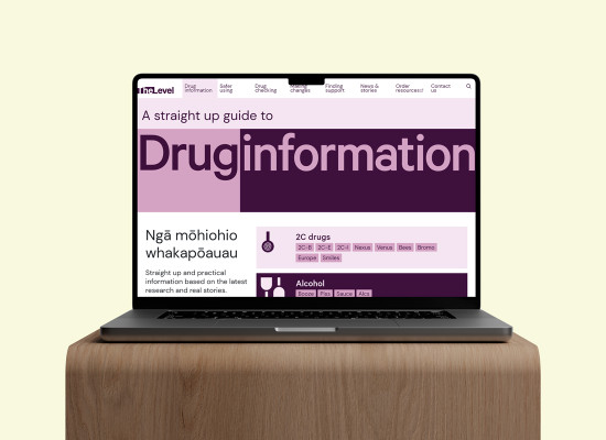 Laptop sitting on surface. Screen shows a purple web page that says "A straight up guide to Drug information".